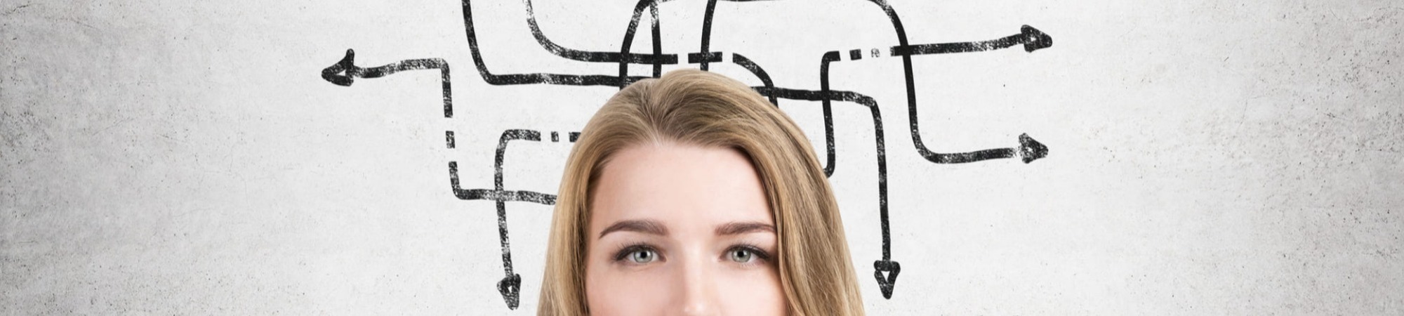 Close up of a thinking woman standing in front of a concrete wall with a black tangled arrows sketch. Concept of decision making.