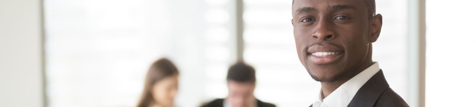 Portrait of smiling businessman looking at camera with colleagues in the background