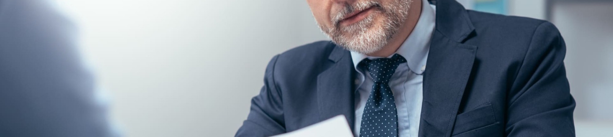 Businessman in office,  reviewing a CV whilst interviewing a job applicant