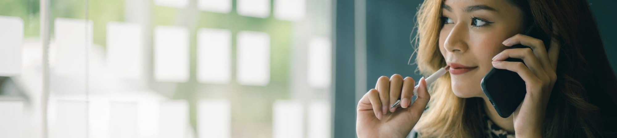 Smiling businesswoman taking on a mobile phone in an office surrounding 