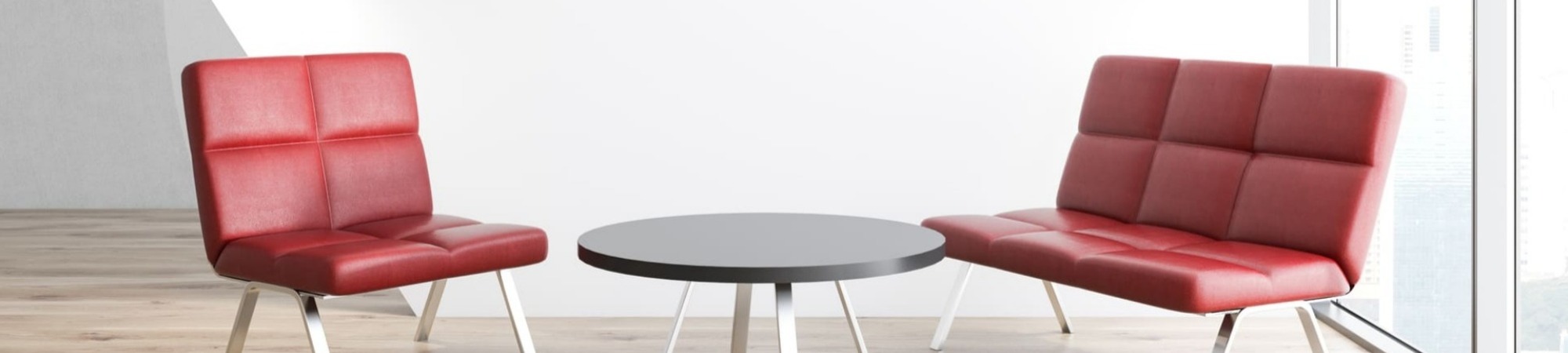 Room with white walls, a wooden floor and two red armchairs positioned near a round coffee table, signifying an interview set up.