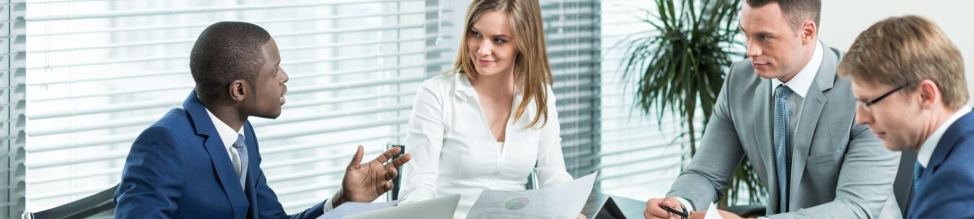 Business professional in meeting room communicating an idea to meeting participants seated around table