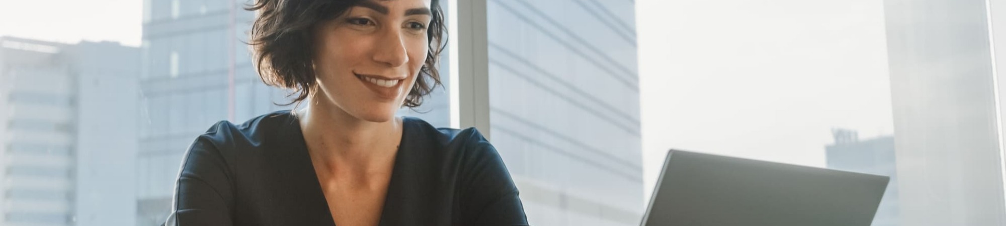 Smiling businesswoman working on a laptop in a modern office. 