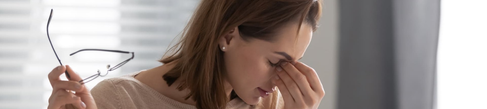 Head shot exhausted female employee took off glasses, massaging nose bridge, suffering from dry eyes syndrome. Tired executive manager feeling pain in eyes, overloaded with computer work at office.