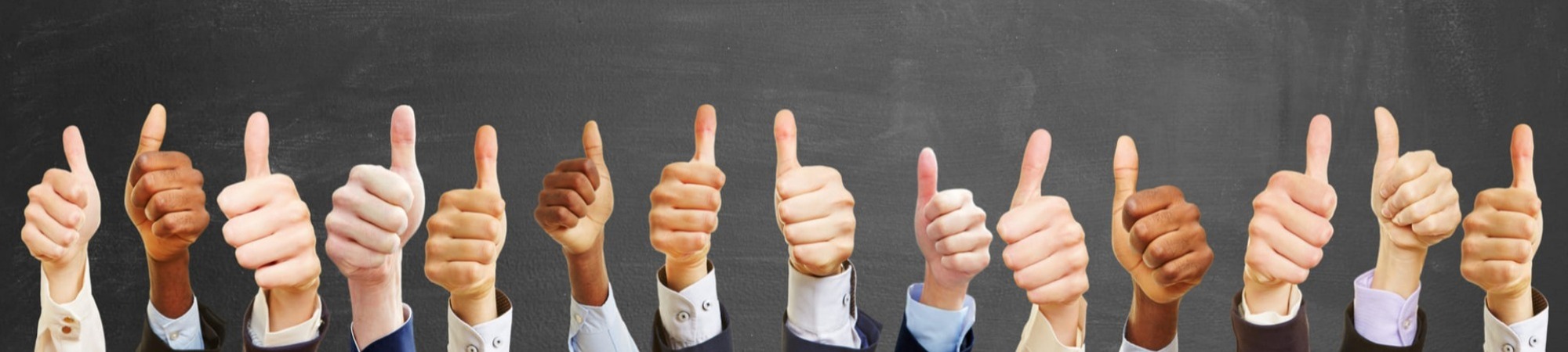 Business group with thumbs up in front of blackboard; only hands and cuffs showing.