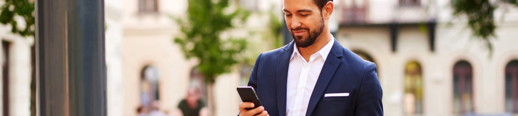 Businessman using his mobile phone and standing on the street